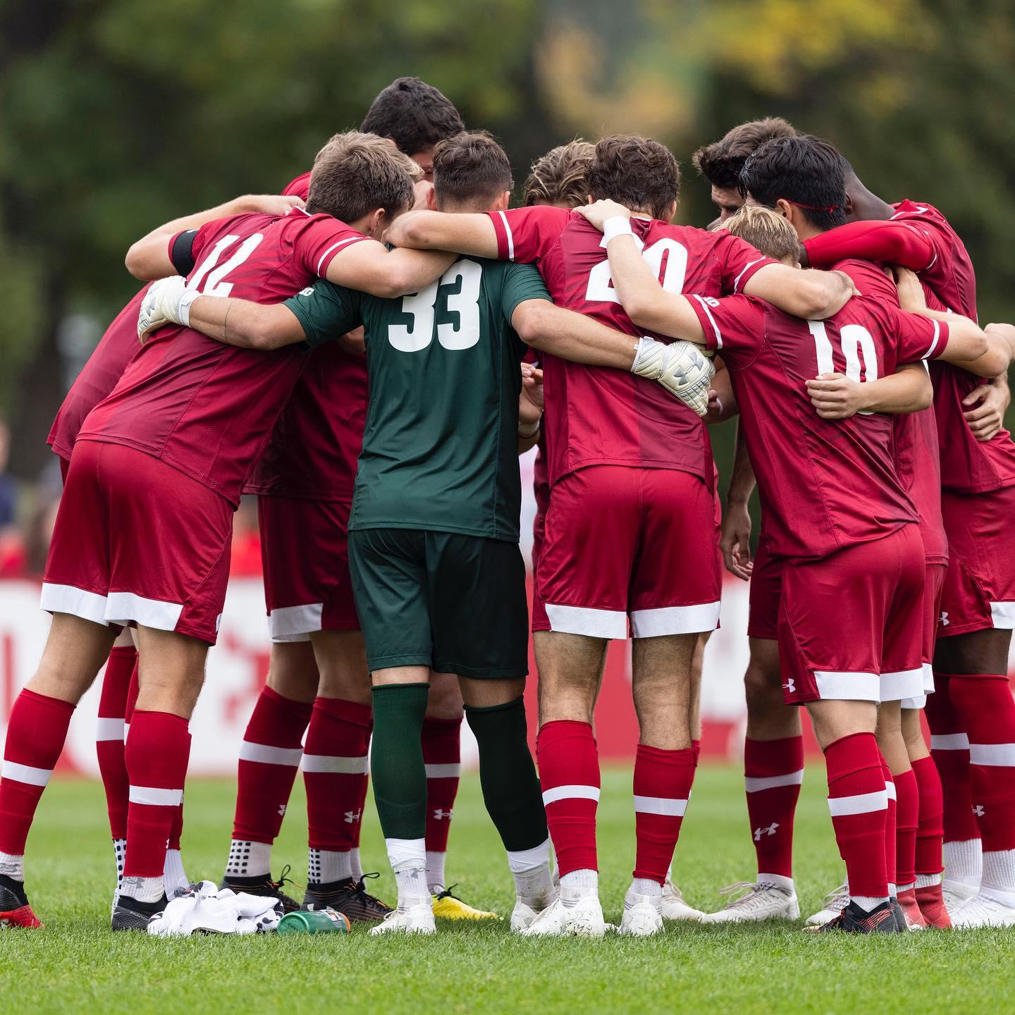 Men in red and white soccer uniforms in a huddle