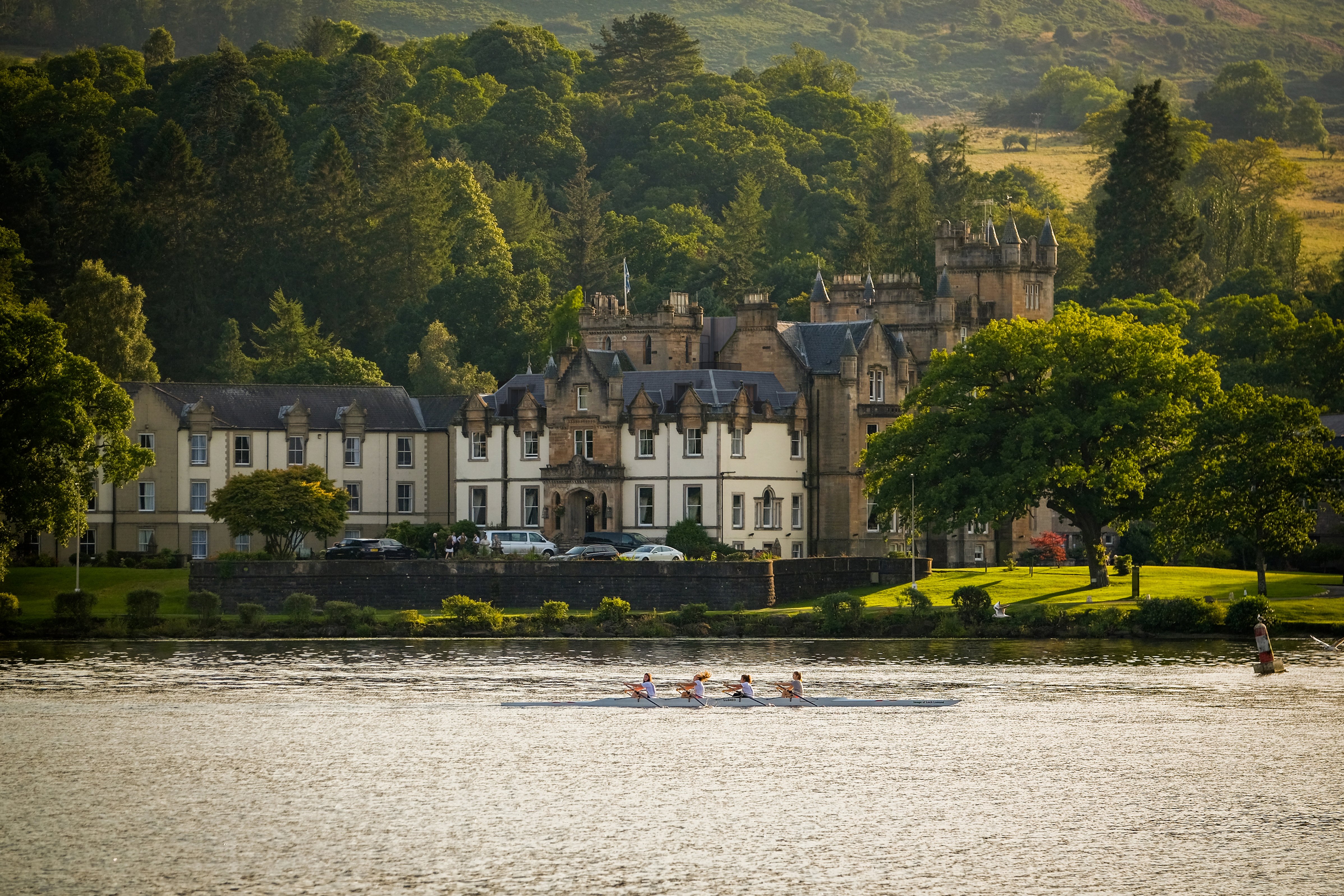 people rowing on the lake in front of Cameron House
