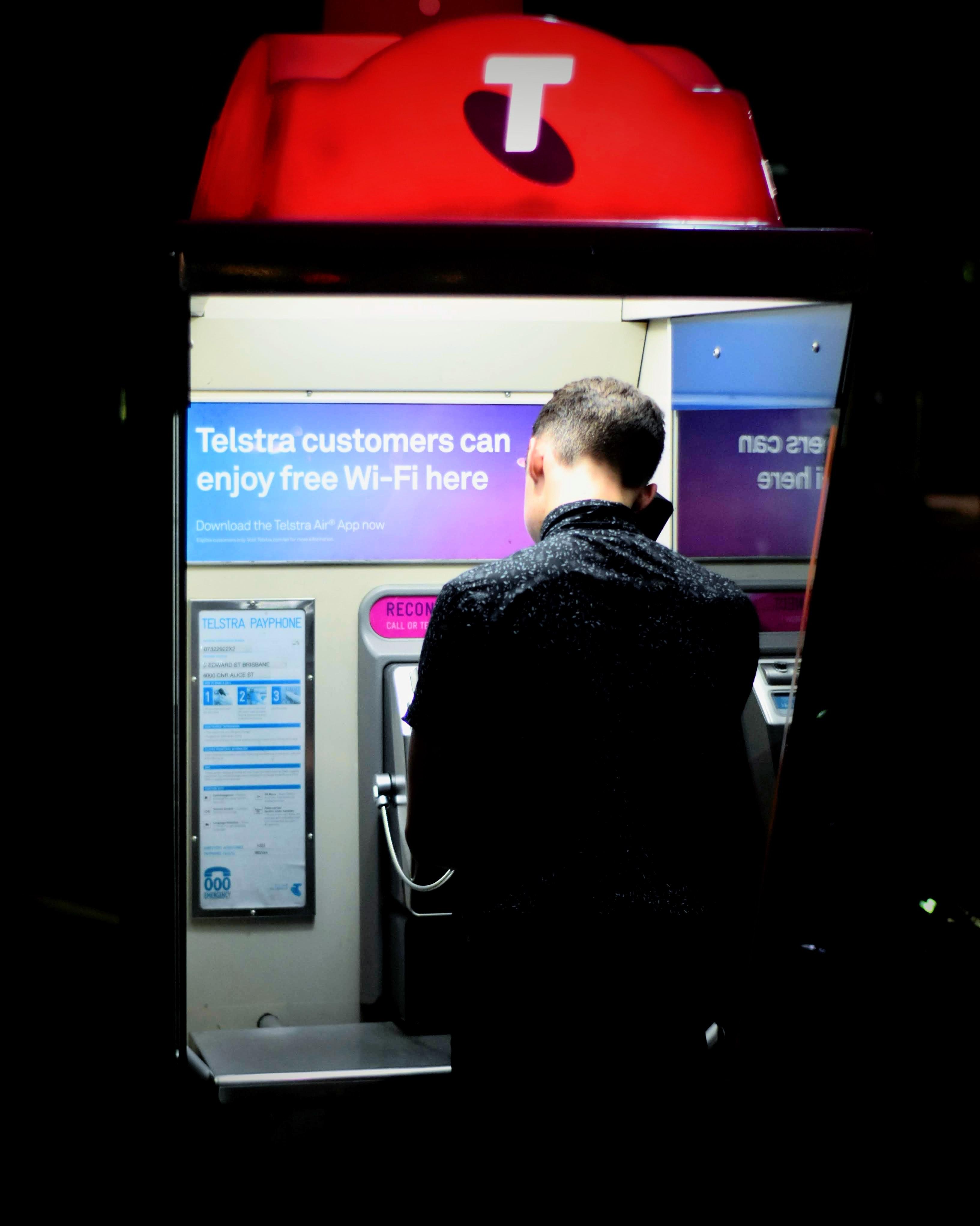 men in black coat using a pay phone