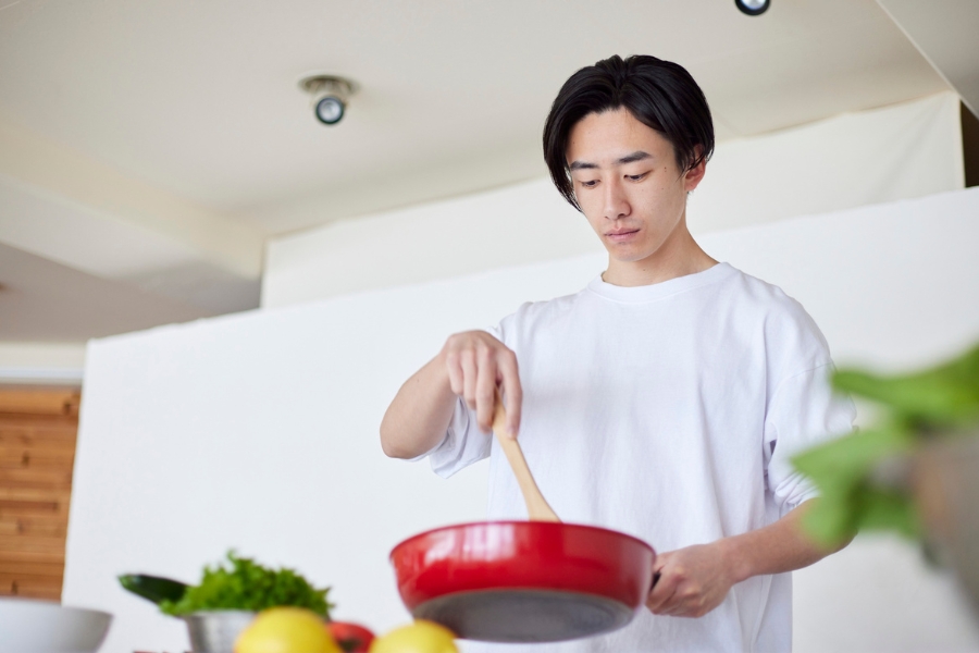Man in a kitchen cooking something in a frying pan