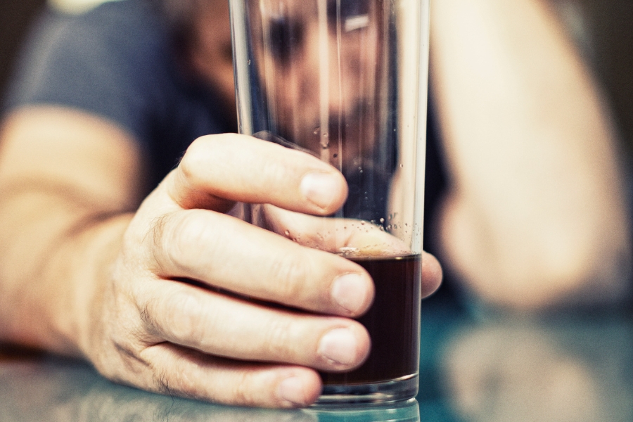 A man holds an alcoholic drink in a glass