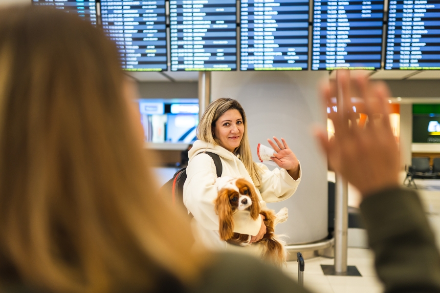 A woman waves goodby in an airport before heading into airport security