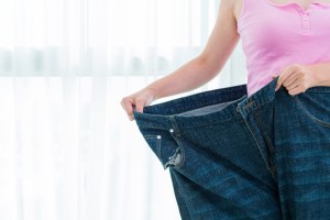 Woman wearing jeans that are many sizes too large, indicating major weight loss