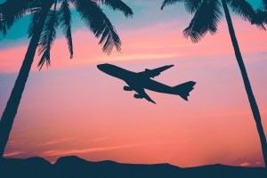 An airplane flying with a sunset behind it