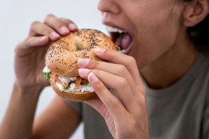 A woman eating a bagel sandwich