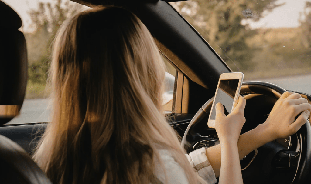 woman driving while looking at phone
