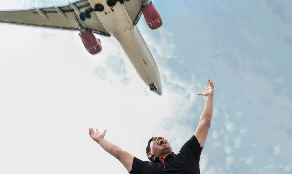 A main raises his arms in triumph while a plane flies overhead.