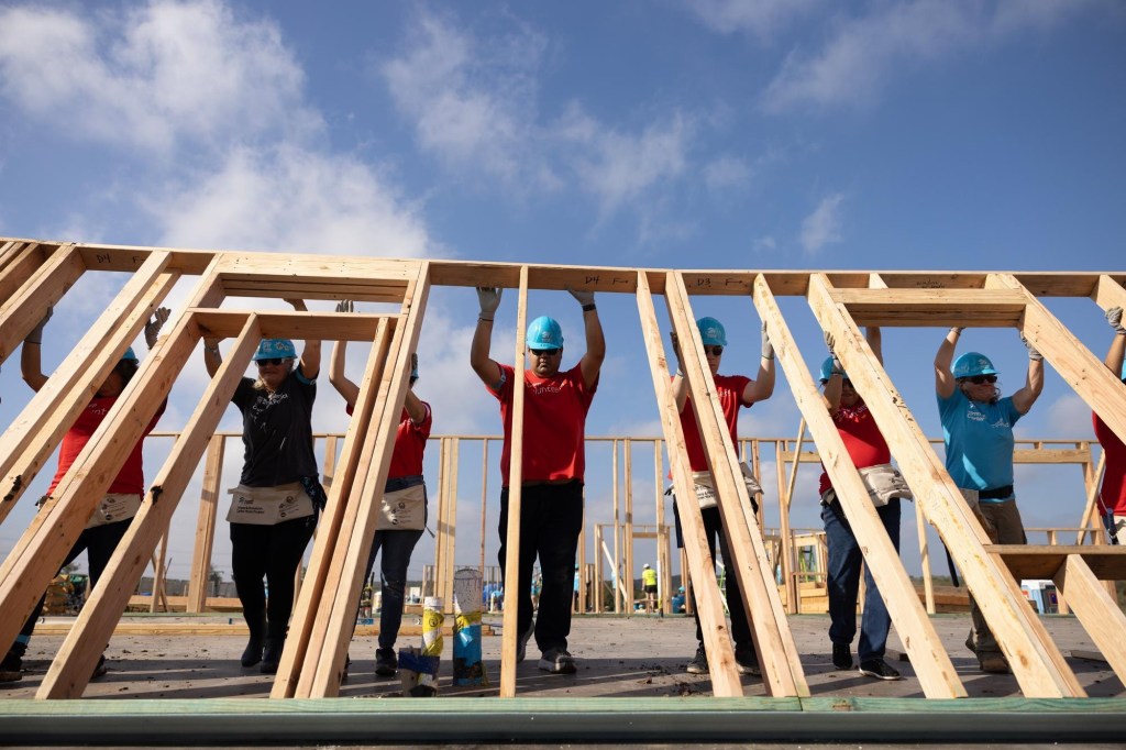 Volunteers raise a wall for the framework of a new home during the first day of building at Habitat for Humanity's 2025 Carter Work Project.