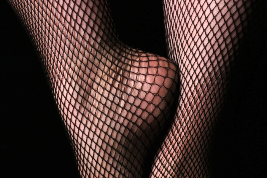 Closeup of a woman's ankles and feet wearing fishnet stockings