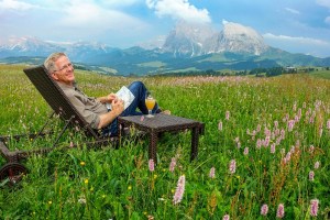 Rick Steves sitting outside in Italy looking at the Dolomites