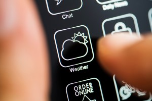 A person pushing the button for a weather app on their phone