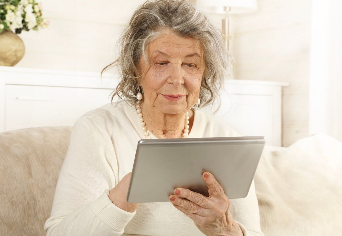 An older woman uses a tablet computer.