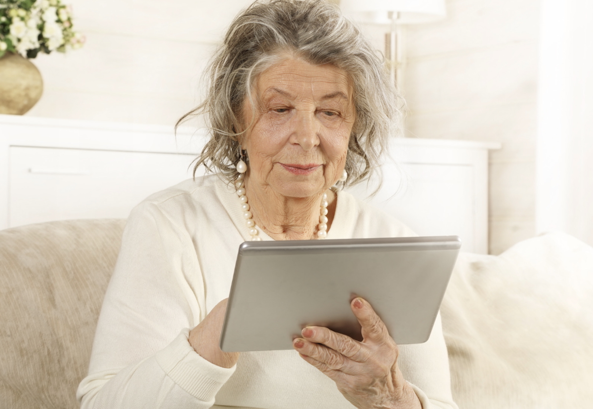 An older woman uses a tablet computer.