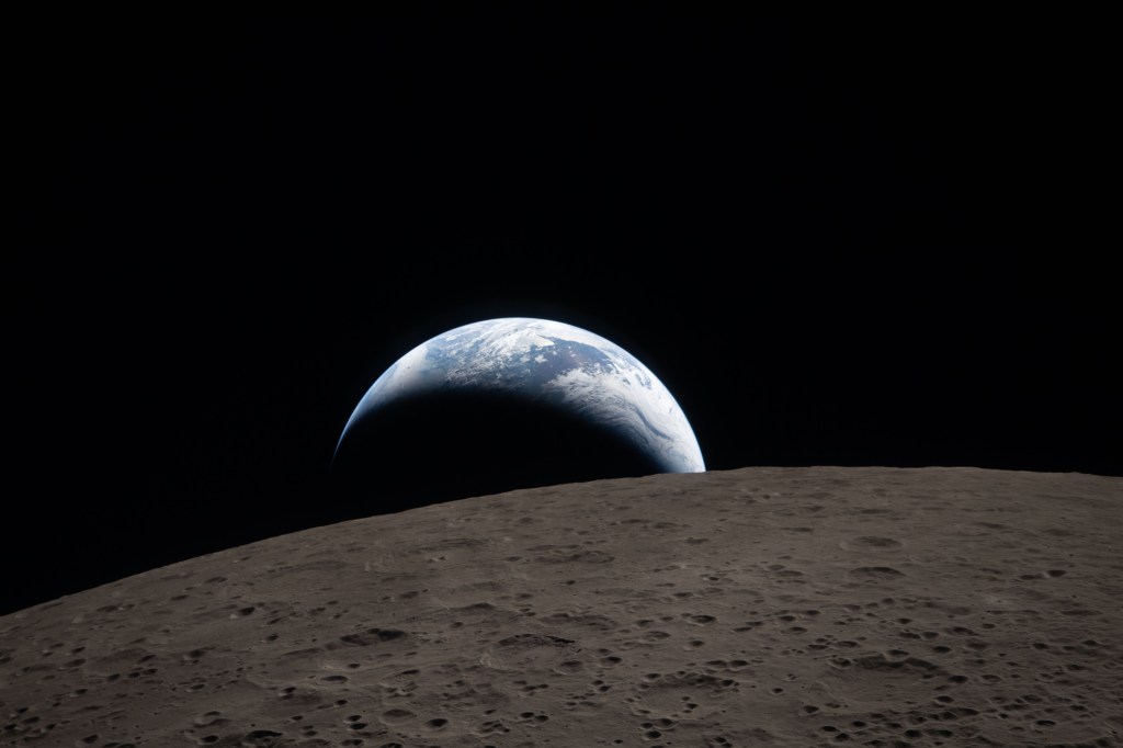 NASA image of the surface of the moon with the Earth lit up in a crescent in the distance