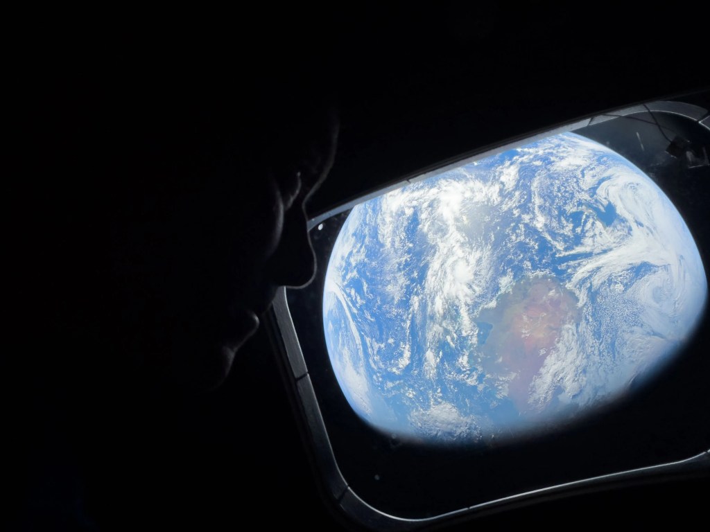 Artemiss II commander Reid Wiseman looks out the window at Earth from the Orion spacecraft 