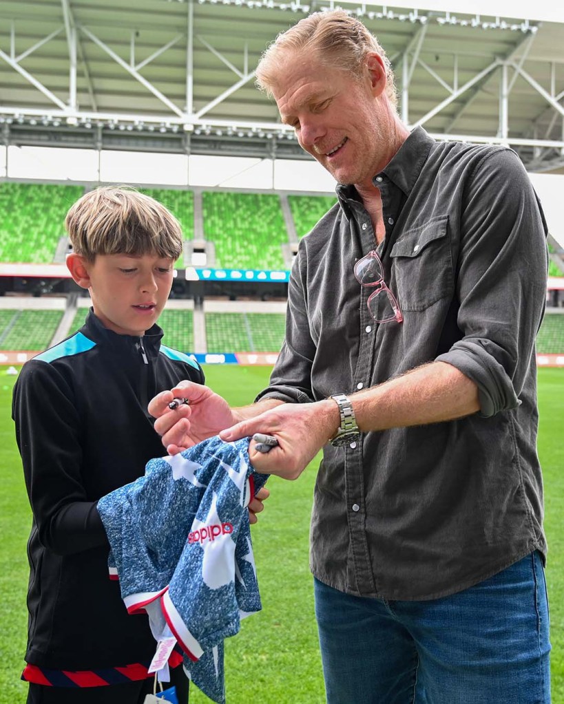 Alexi Lalas signing jersey for young fan.