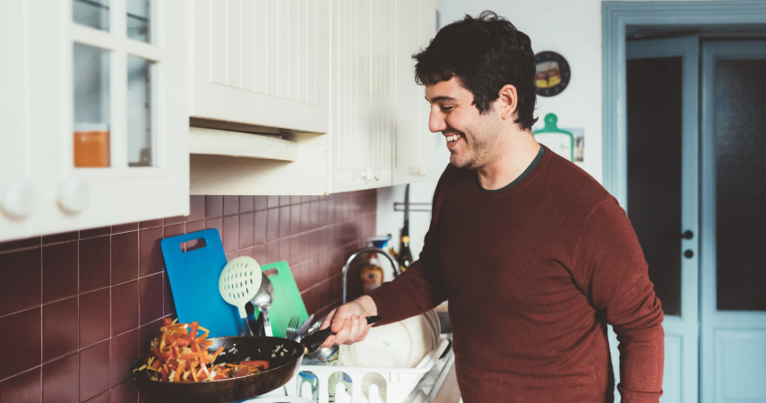 man cooking, leaning to cook,frying pan, man in kitchen, stir fry