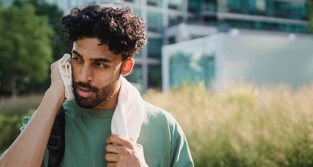 man with beard, curly hair, hot day, towel on nexk, green shirt