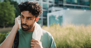 man with beard, curly hair, hot day, towel on nexk, green shirt