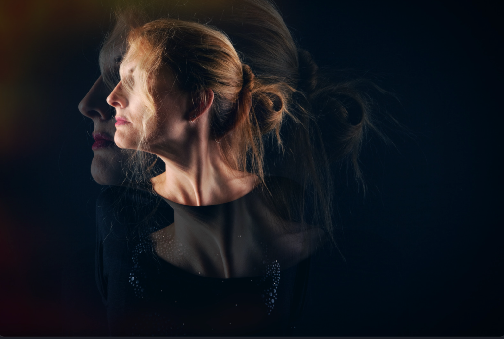 A double exposure portrait of a woman on a black background.