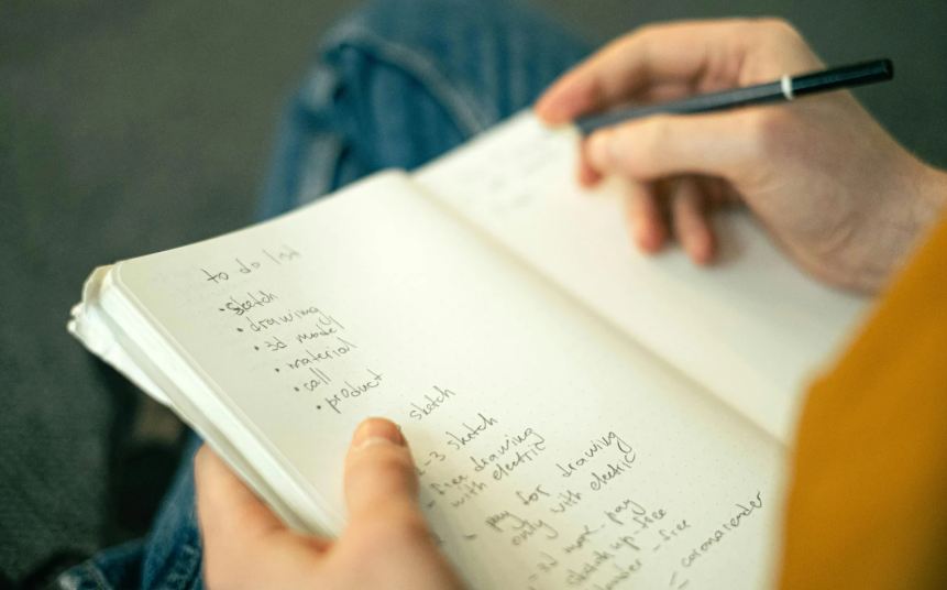 list, notebook, man with pen, writing list, thumbs