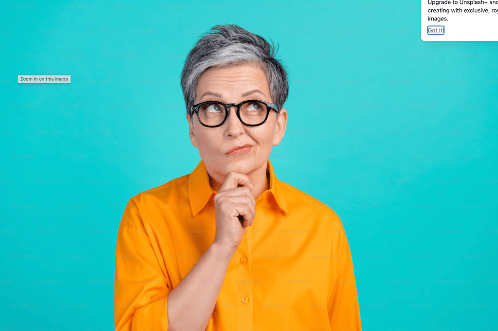 Older woman with short gray hair and glasses, wearing an orange button-down shirt, looking up thoughtfully with her hand on her chin against a teal background
