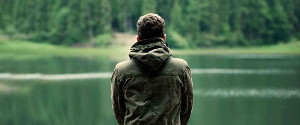 man in nature, looking at pond, man in parka
